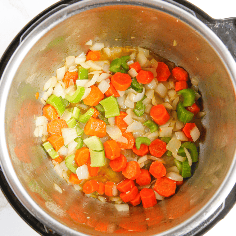 Sautéing diced onion, carrots, celery, and garlic in melted butter until softened and fragrant.