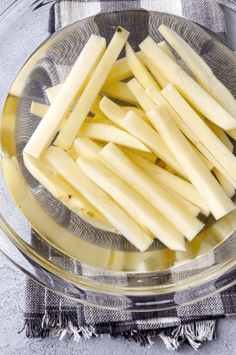 Cut fries rinsed, soaked, patted dry, and seasoned for cooking.