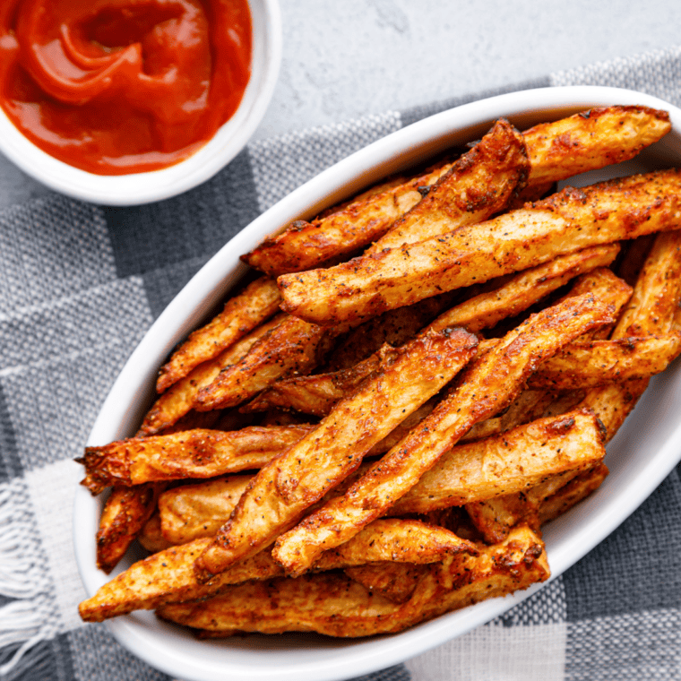 Close-up of crispy, golden fries sprinkled with Copycat Checkers Seasoned Fries spice, served in a bowl.