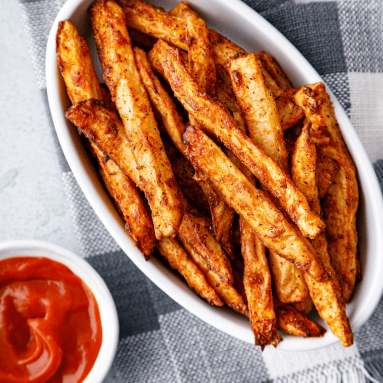 Close-up of a bowl of crispy, golden fries generously dusted with Copycat Checkers Seasoned Fries Spice.