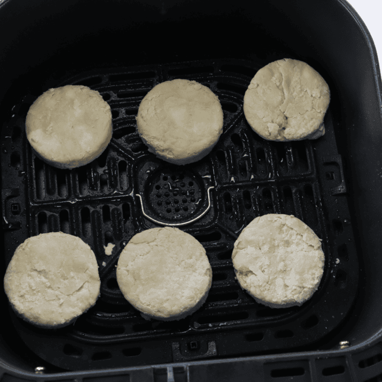 Placing biscuits in air fryer basket and cooking until golden.