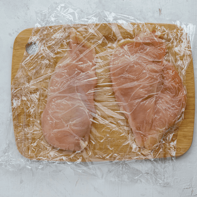 Flattening chicken breasts to an even thickness and seasoning with salt, pepper, and flour.