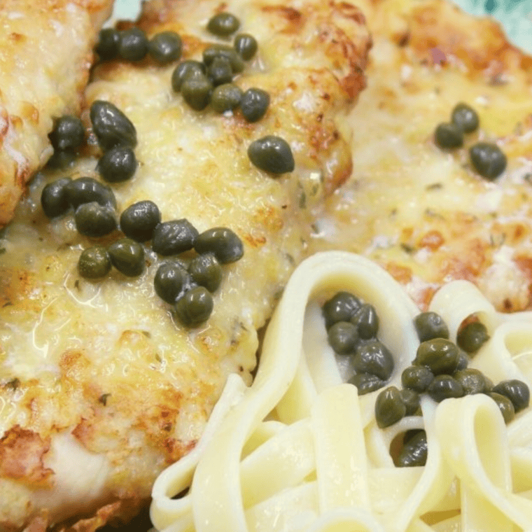 Plate of Maggiano's Chicken Piccata: Golden-brown chicken breast in a tangy lemon butter sauce with capers, served with pasta and garnished with parsley.