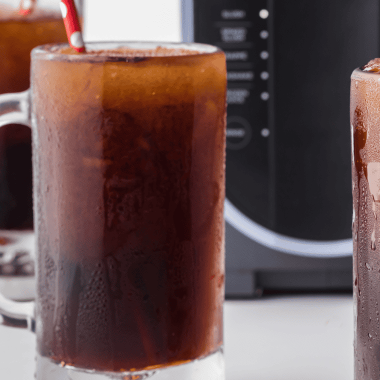 Close-up of a Ninja Slushi Root Beer Float Slush in a glass with creamy foam on top, a refreshing dessert drink.