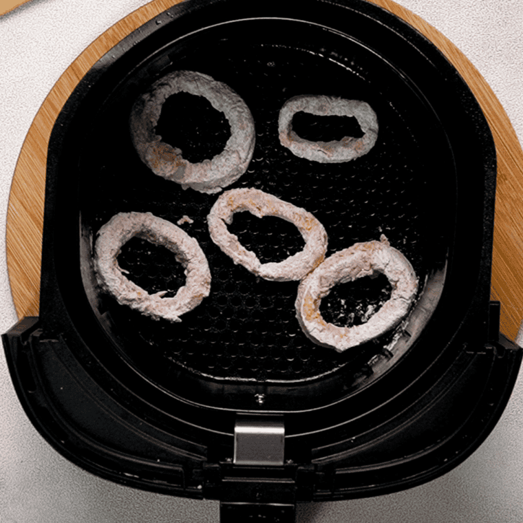 Spraying calamari with oil and air frying for 8-10 minutes, shaking halfway for golden, crispy perfection.