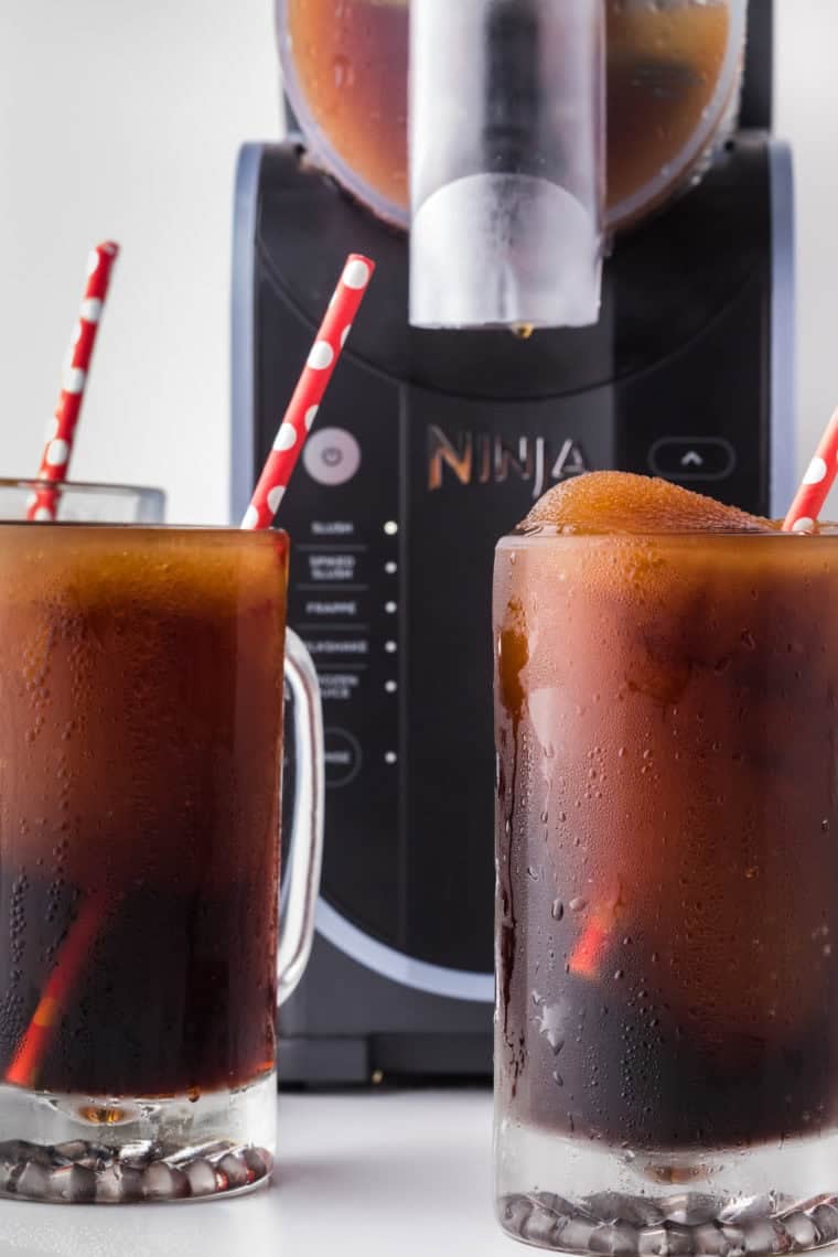 A glass of Ninja Slushi Root Beer Float Slush topped with frothy foam, a refreshing and fun drink perfect for hot days.