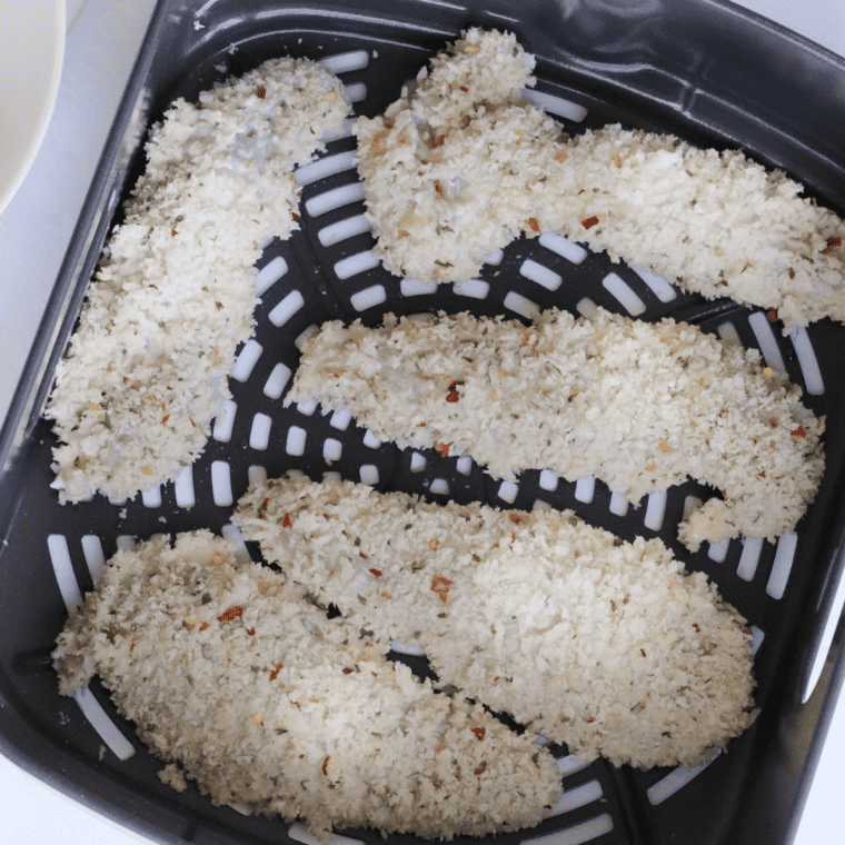 Arranging coated chicken tenders in air fryer basket, air frying at 375°F for 10-12 minutes until crispy.