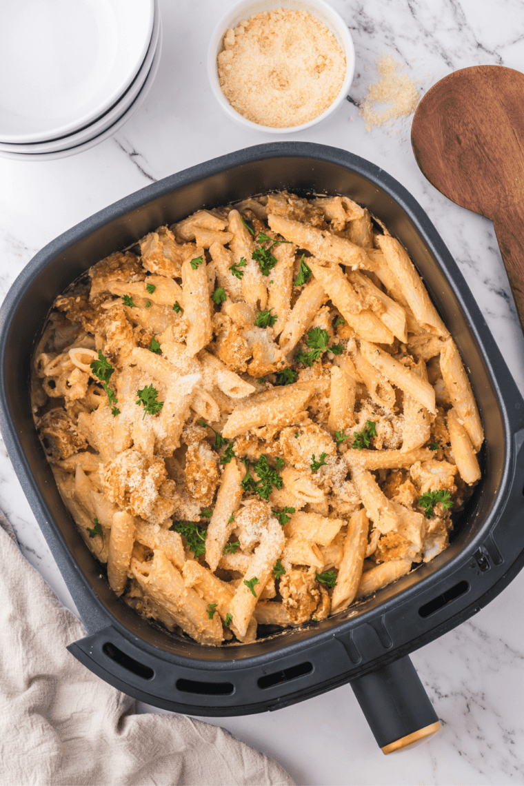 A creamy plate of Air Fryer Buffalo Chicken Pasta topped with parsley, featuring crispy chicken tenders and flavorful buffalo sauce.