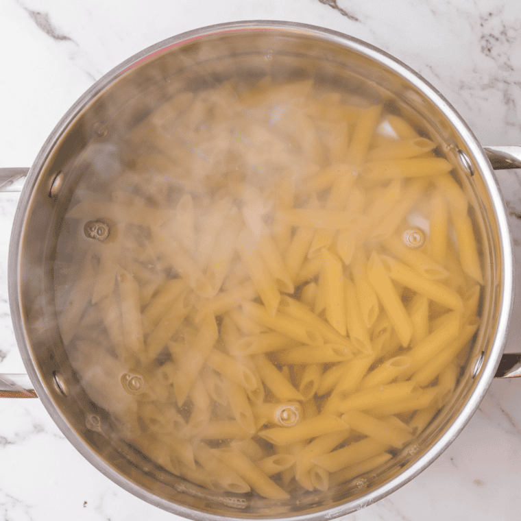 Boiling salted water and cooking penne pasta until al dente, then draining.