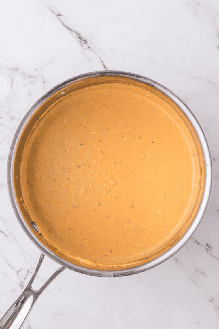 Heating vegan buffalo dip and mixing with cream cheese until smooth and creamy.