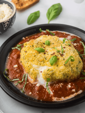 Crispy, golden-brown Air Fryer Burrata with a gooey, cheesy center, served on a plate with fresh basil and marinara sauce.