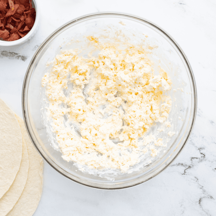 Mixing cream cheese, cheddar cheese, and mayo in a bowl until smooth.