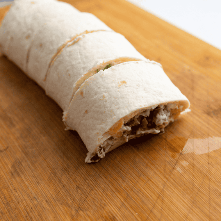 Rolling tortillas tightly and slicing into 1-inch pieces.