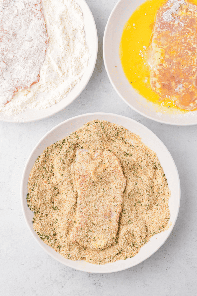 Coating veal cutlet with breadcrumb mixture, pressing gently to adhere.