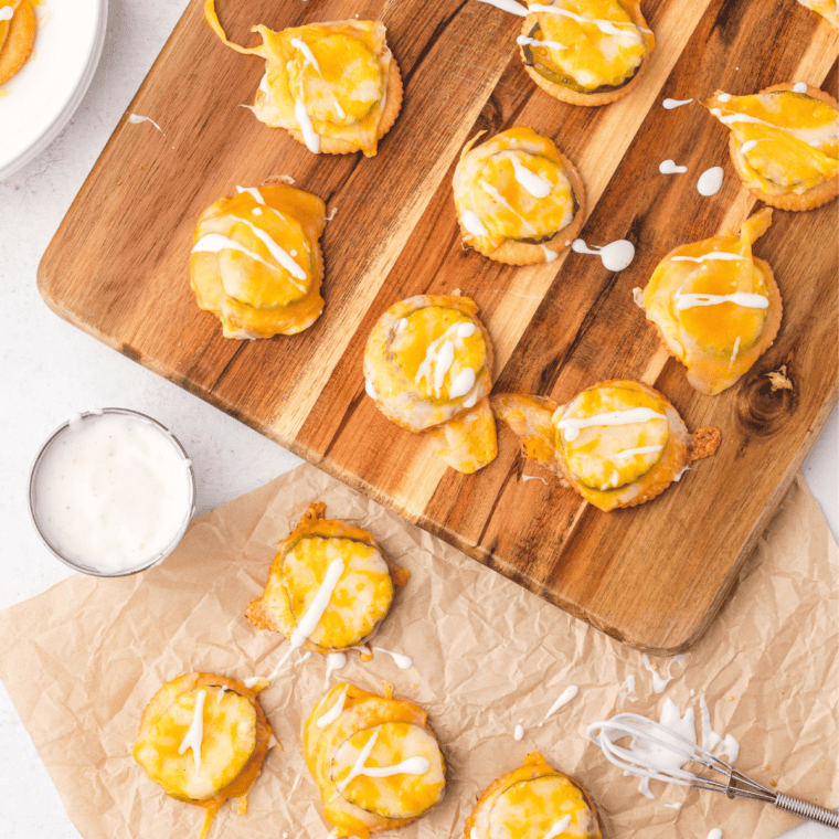 A plate of golden, crispy Cheesy Ritz Pickle Bites with melted cheese and tangy pickles between buttery Ritz crackers.