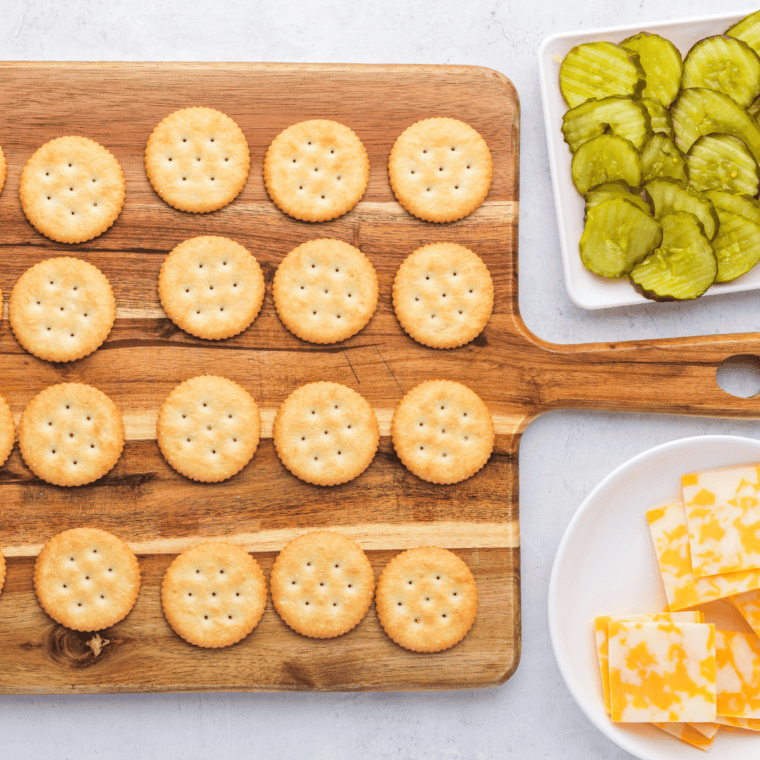 Ritz cracker topped with a pickle chip and Colby Jack cheese slice.