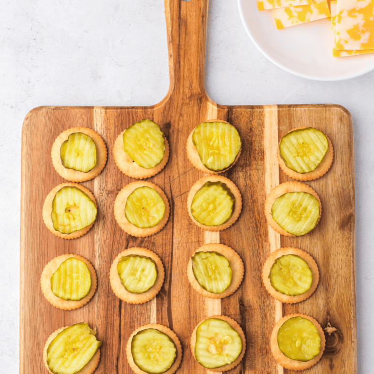 Assembling Cheesy Ritz Pickle Bites with crackers, pickles, and cheese.