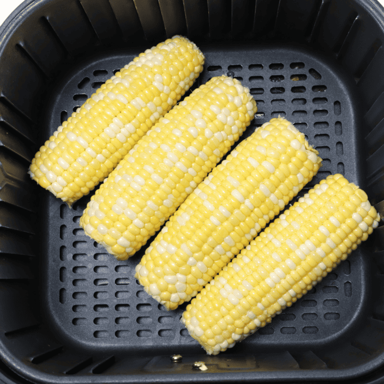 Placing corn in air fryer basket, cooking at 400°F for 12-15 minutes, turning halfway until golden and charred