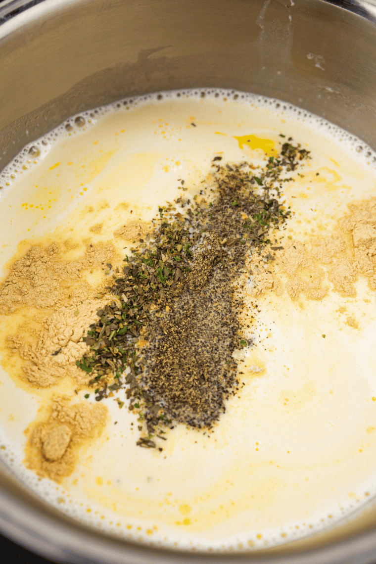  Stirring grated Parmesan cheese into a creamy Alfredo sauce, ensuring it melts smoothly. Seasoning with salt and white pepper for enhanced flavor.