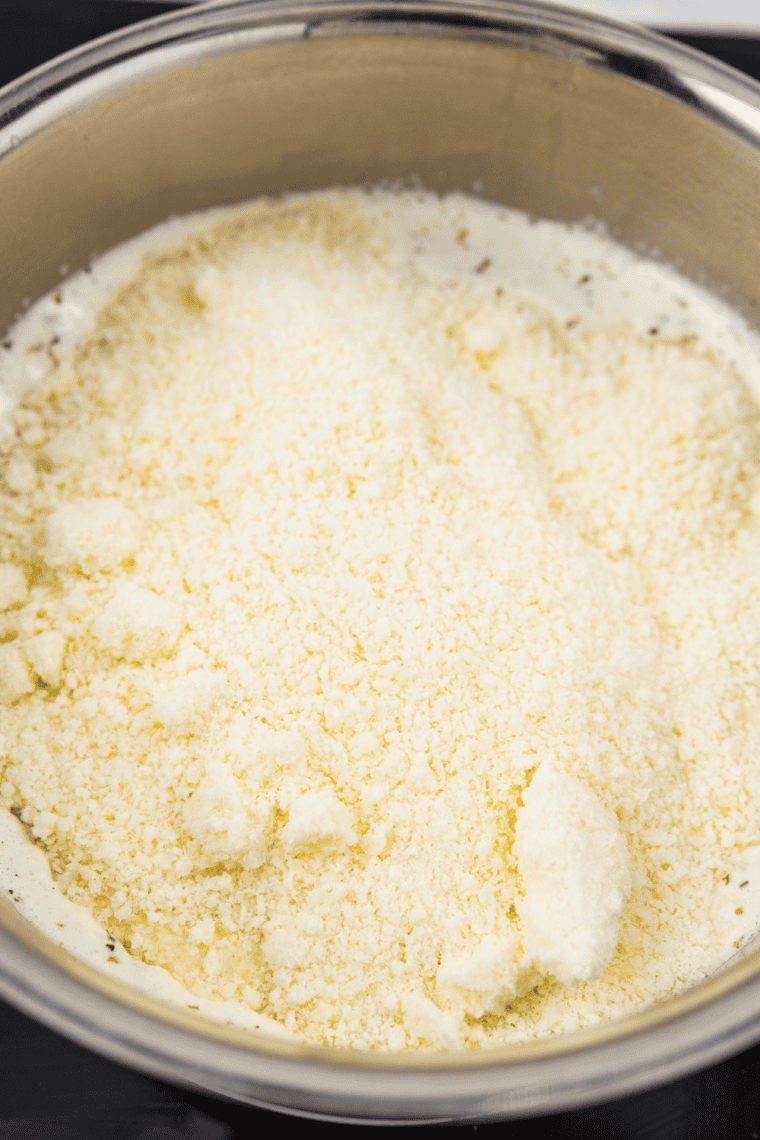 Smooth and creamy Alfredo sauce with melted Parmesan, salt, and white pepper being stirred to perfection.