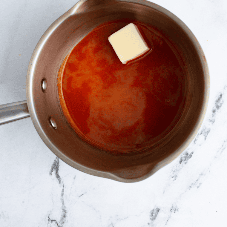 Mixing Frank's Red Hot, apple cider vinegar, mustard, and spices in a saucepan.