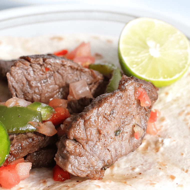 A sizzling plate of Copycat Chili’s Steak Fajitas with juicy marinated steak, sautéed peppers, and onions, served with warm tortillas.