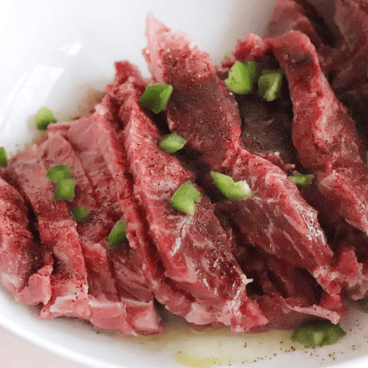  Mixing lime juice, oil, garlic, cumin, brown sugar, salt, and pepper in a bowl to marinate flank steak, then refrigerating for enhanced flavor.