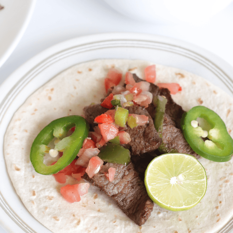 Copycat Chili’s steak fajitas with juicy marinated flank steak, bell peppers, onions, and tasty sides like pico de gallo, guacamole, and sour cream.