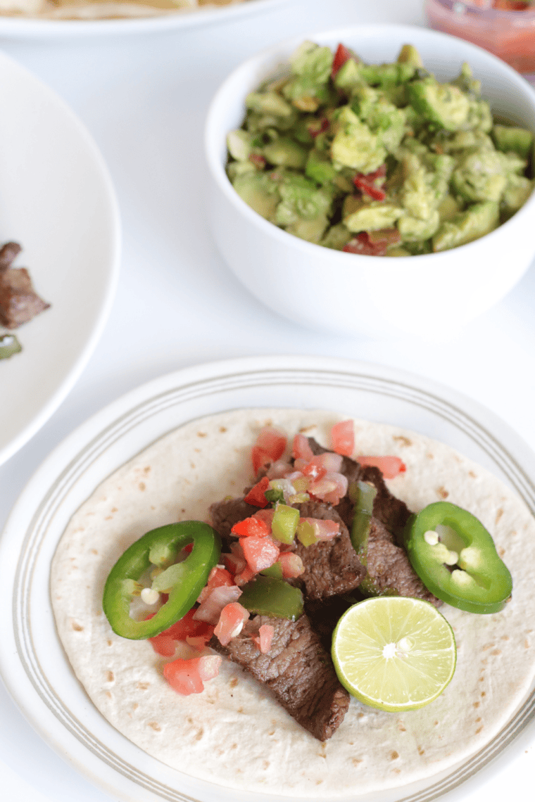 Copycat Chili’s Steak Fajitas served with seasoned steak, bell peppers, onions, and fajita sides like pico de gallo, guacamole, and cheddar cheese.