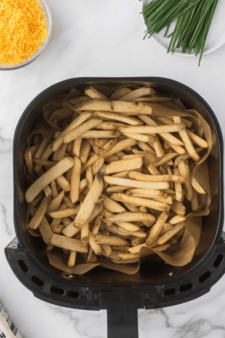 Air fryer basket filled with frozen French fries cooking at 400°F until crispy and golden brown.