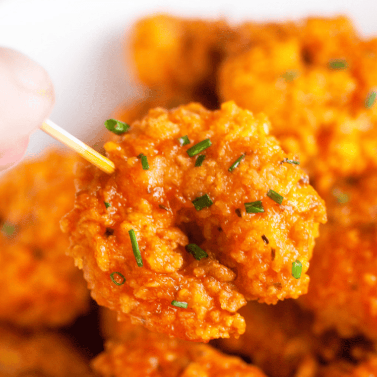 Crunchy, golden copycat Popeyes popcorn shrimp served with dipping sauce on a plate.