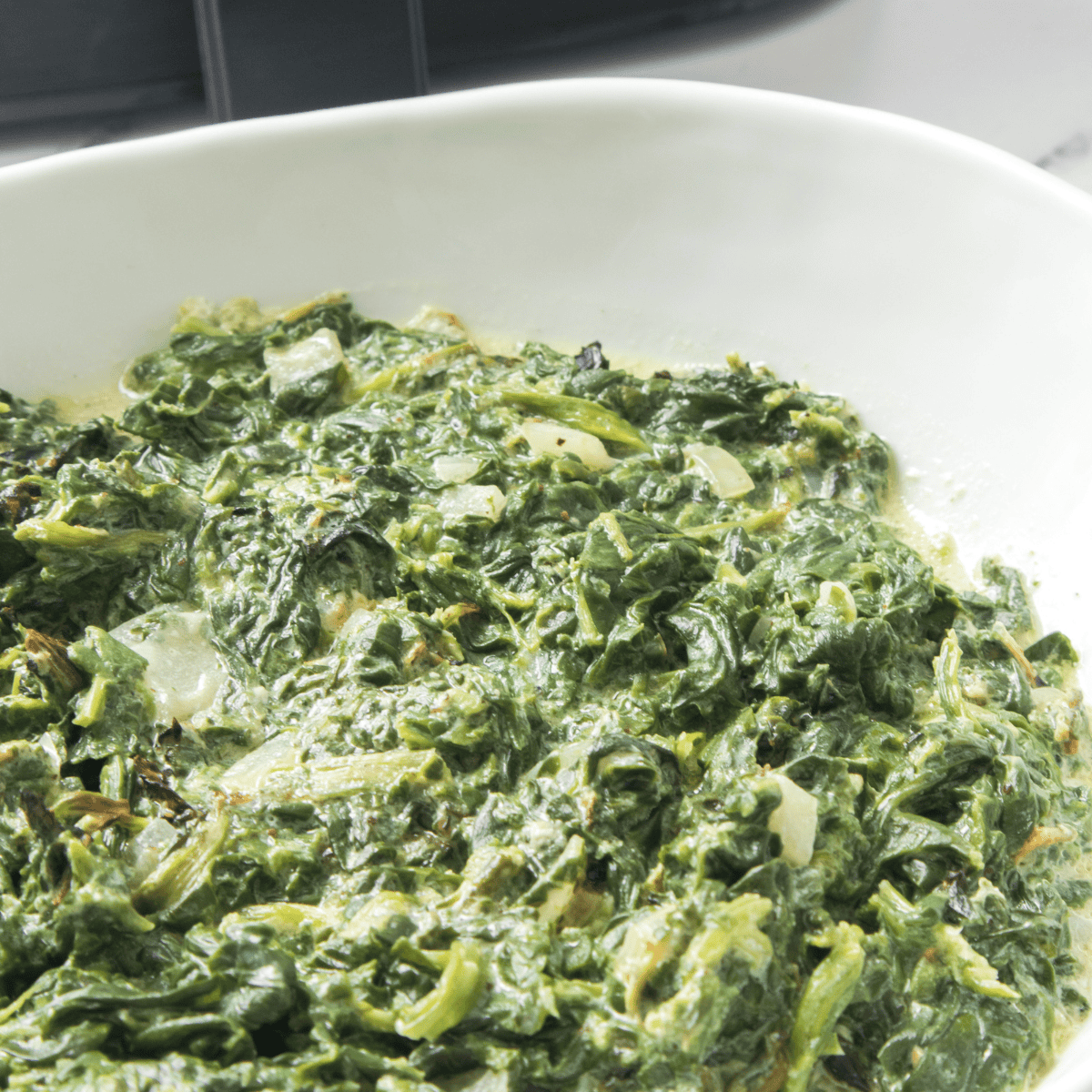 A creamy bowl of Easy Creamed Spinach, made with fresh spinach, garlic, cream cheese, and Parmesan, ready to serve.