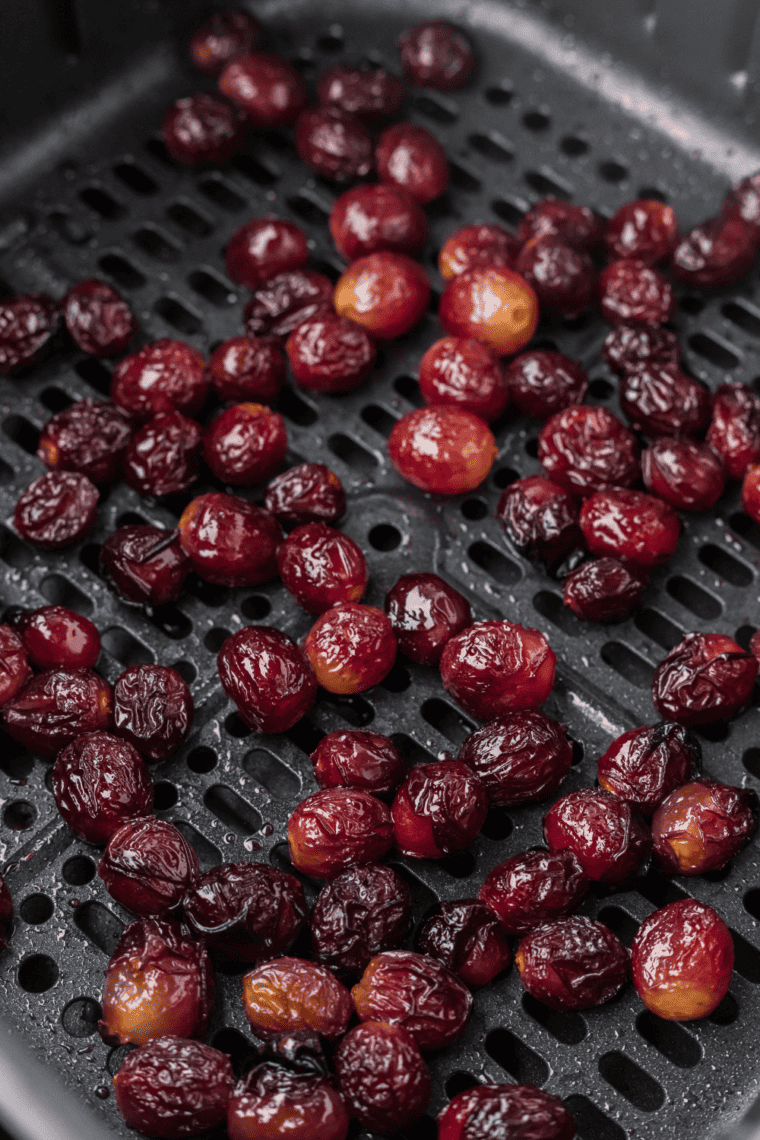 Fresh grapes arranged in an air fryer basket for dehydration to make homemade raisins.