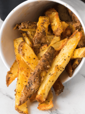 A plate of homemade LongHorn Steakhouse-style fries, golden and crispy, served with a dipping sauce.