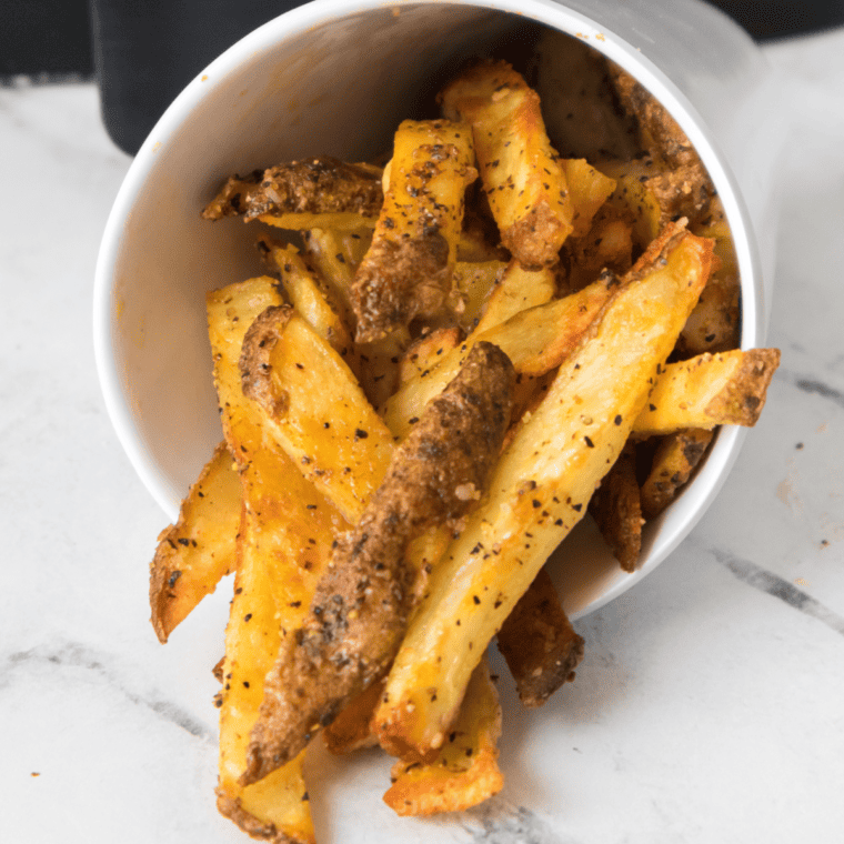 A plate of homemade LongHorn Steakhouse-style fries, golden and crispy, served with a dipping sauce.