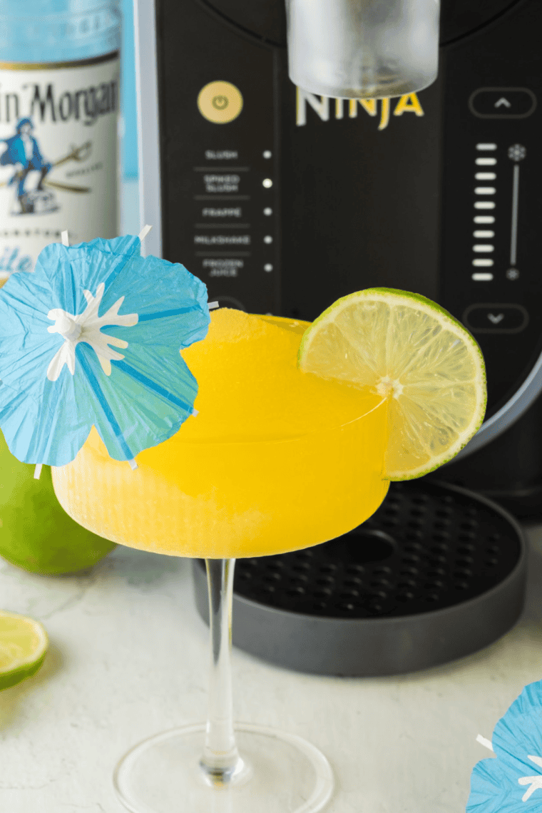 A vibrant and frosty Ninja Slushi Mango Daiquiri served in a glass, garnished with lime and mango.