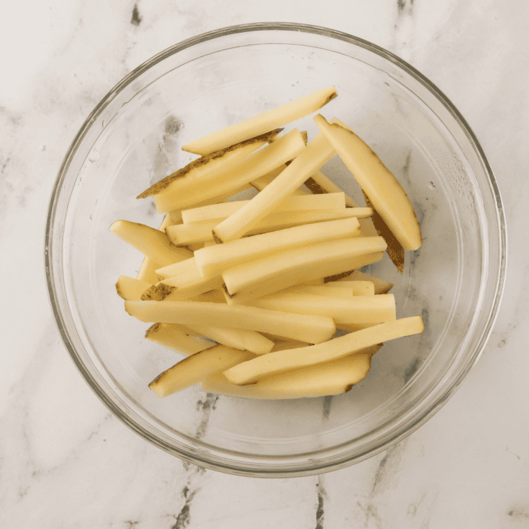 Wash and scrub russet potatoes, then slice into thick wedges.