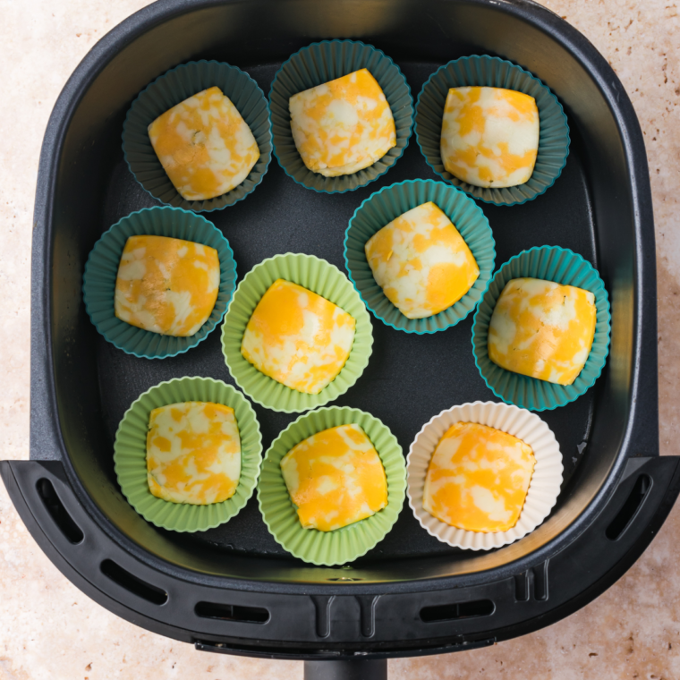Small squares of cheese placed into muffin tin cups, ready for air frying.