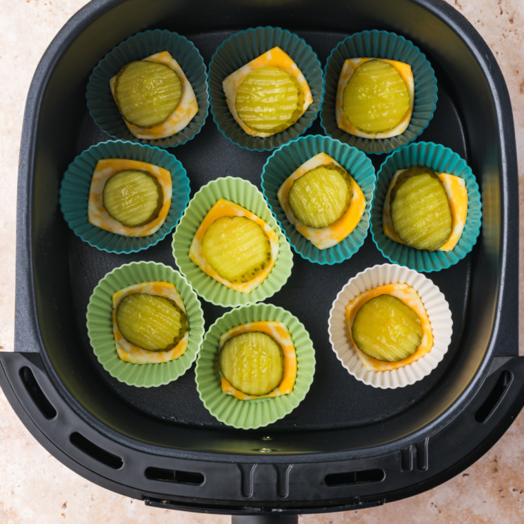 Pickle chip layered over cheese in muffin tin, sprinkled with ranch seasoning and topped with more shredded cheese.