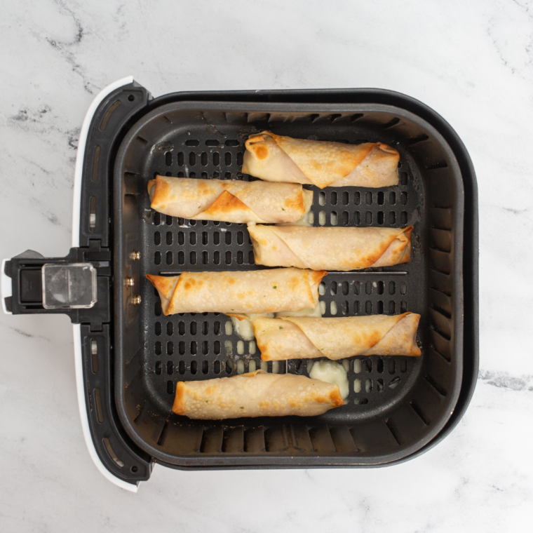 Lightly spraying wontons with olive oil, placing them in an air fryer basket in a single layer, and setting the air fryer to 375°F for 6-8 minutes.