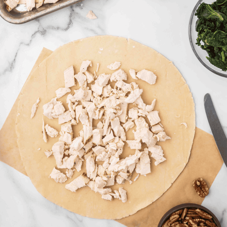 Spread the cooked, diced chicken over the pie crust.