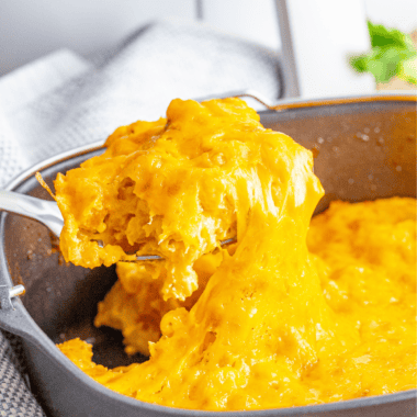 Bowl of creamy 3 cheese mac and cheese topped with melted cheese and herbs.