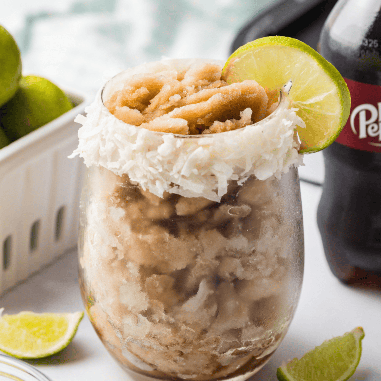 Refreshing Ninja Creami Dirty Dr Pepper Slush with coconut and lime in a clear glass, ready to enjoy
