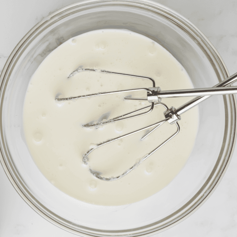 Stirring heavy cream and whole milk into the cream cheese mixture until smooth and well combined