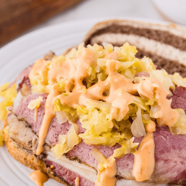 Sliced homemade pastrami with a black pepper and spice crust on a wooden cutting board