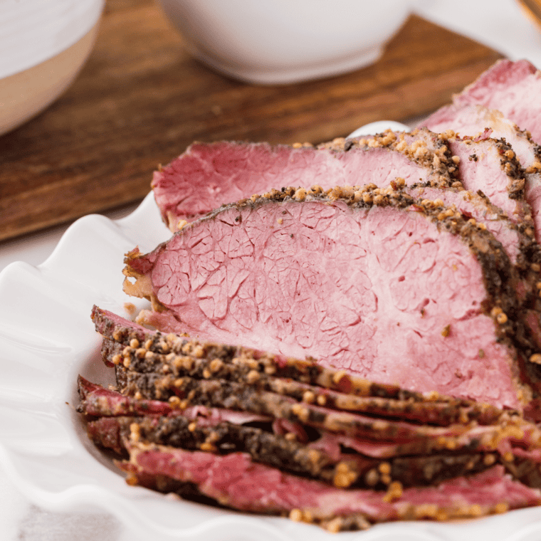 Tender slow-cooked pastrami sliced on a wooden cutting board, ready for sandwiches