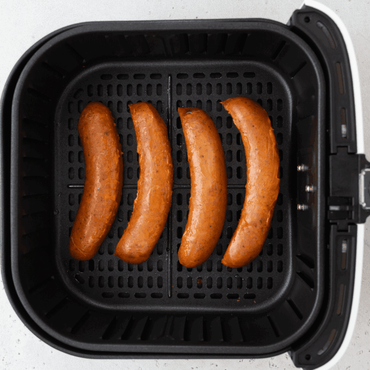 Placing chorizo sausages in the air fryer basket and cooking until the internal temperature reaches 145°F.