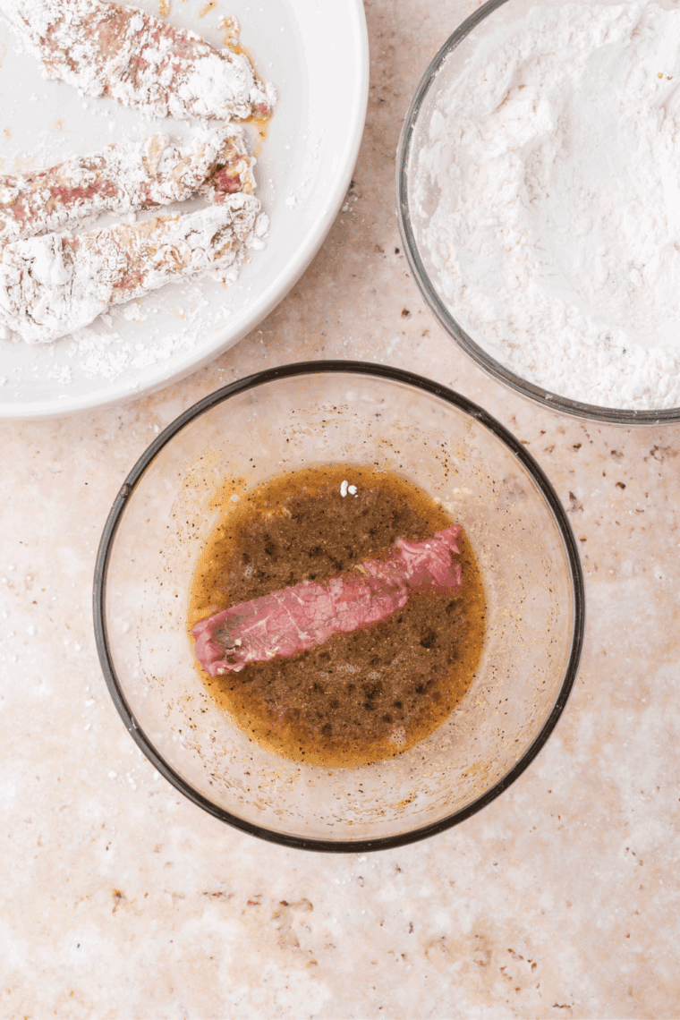 Mixing cornstarch and flour, dipping beef into egg mixture for coating.