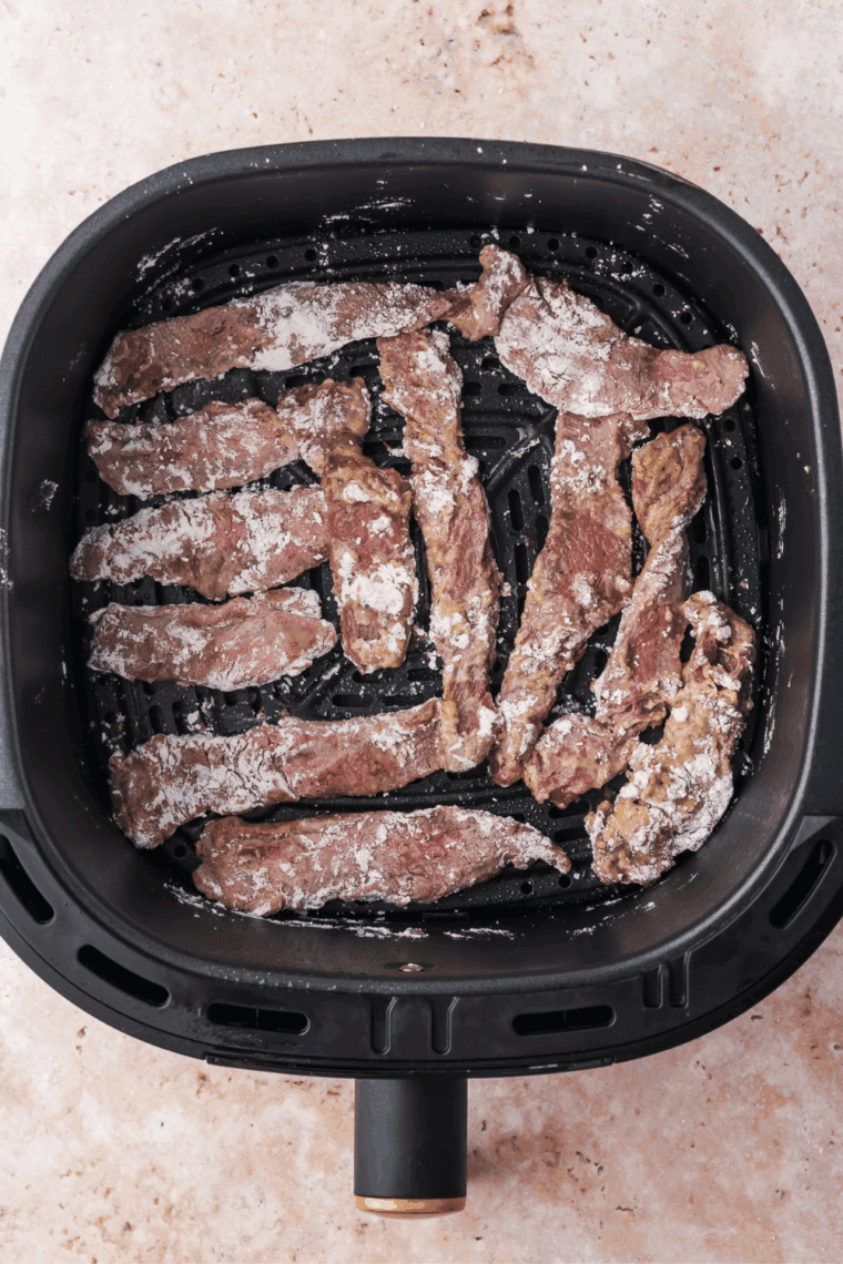 Arranging meat in the air fryer basket, and cooking until fully cooked.