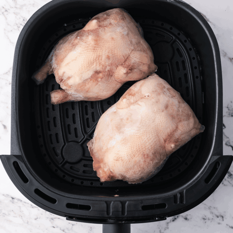 Placing frozen Cornish hens in the air fryer basket, breast side down, air frying at 360°F for 30 minutes to start cooking.